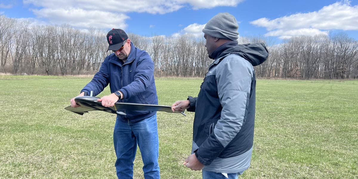 two men inspecting drone in hand