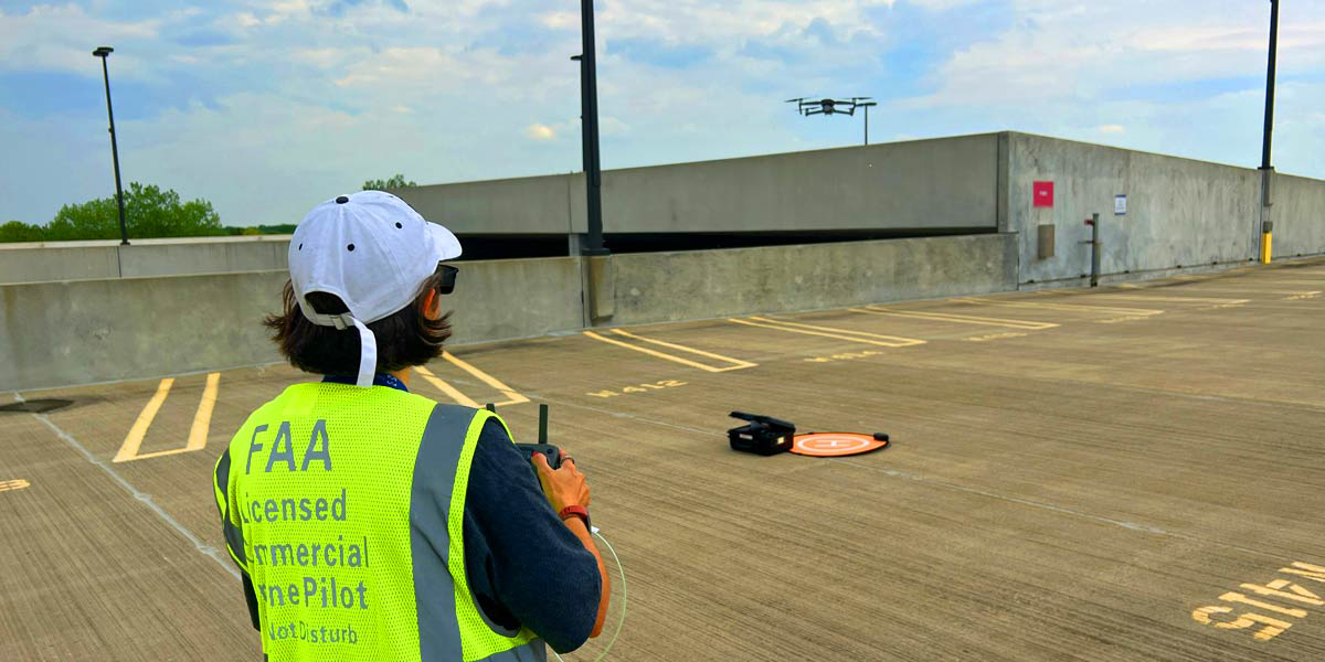 woman with hat flying a drone over building